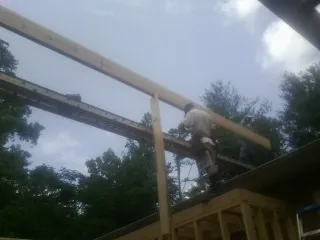 Carpenter setting a ridge beam over a new addition frame — Ice Dam Removal by Roofing Brothers in Rawlings
