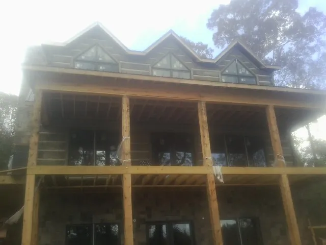 Dormers and porch framing on a large log home under construction — Roof Coating work by our crew in Rawlings
