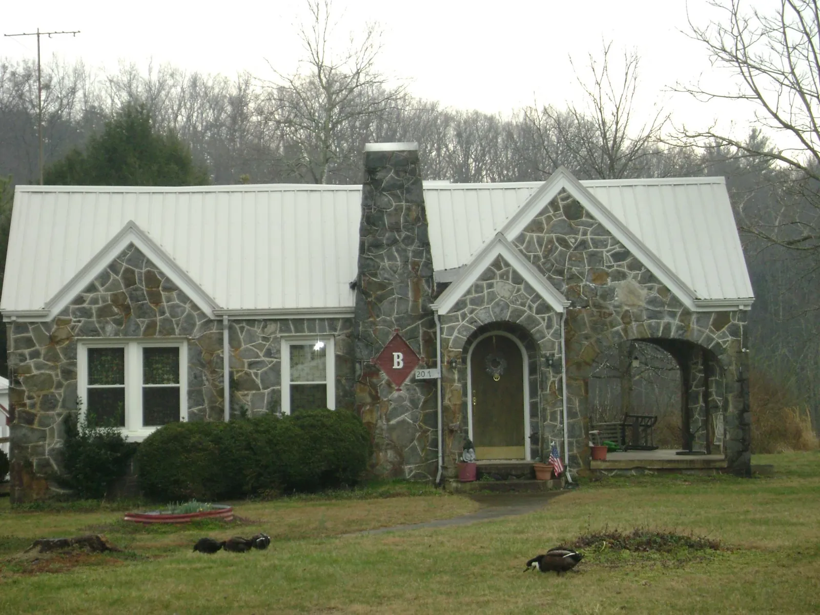 White metal roof on a stone cottage with steep gables in Rawlings