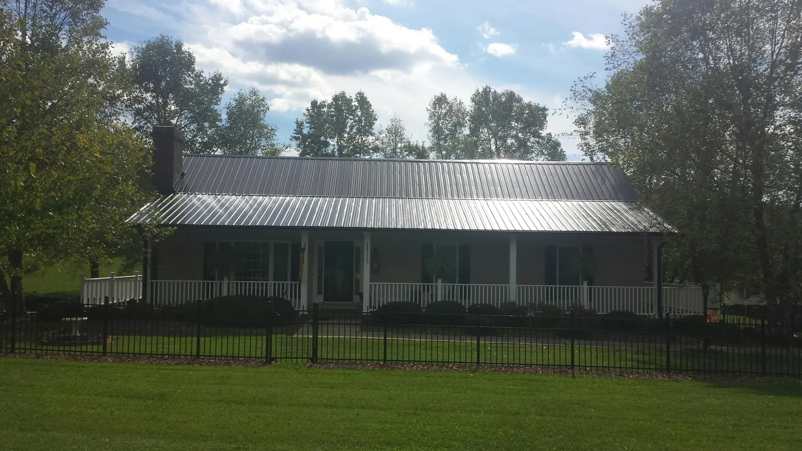 Gray metal roof on a brick ranch with a full width front porch — Gutter Guard Installation work by our crew in Rawlings